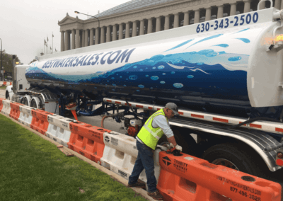 Tank Truck with Laborer Filling Barricades with Bulk Water