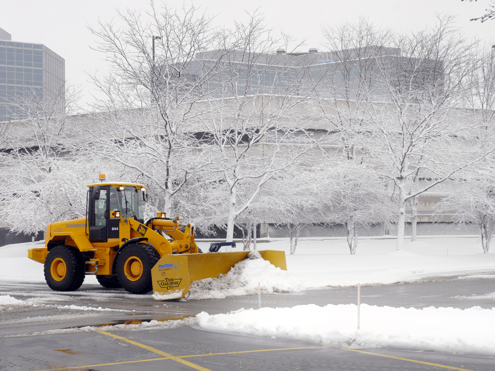 A Gasaway Maintenance Company plow truck clearing out a snow-covered commercial parking lot.