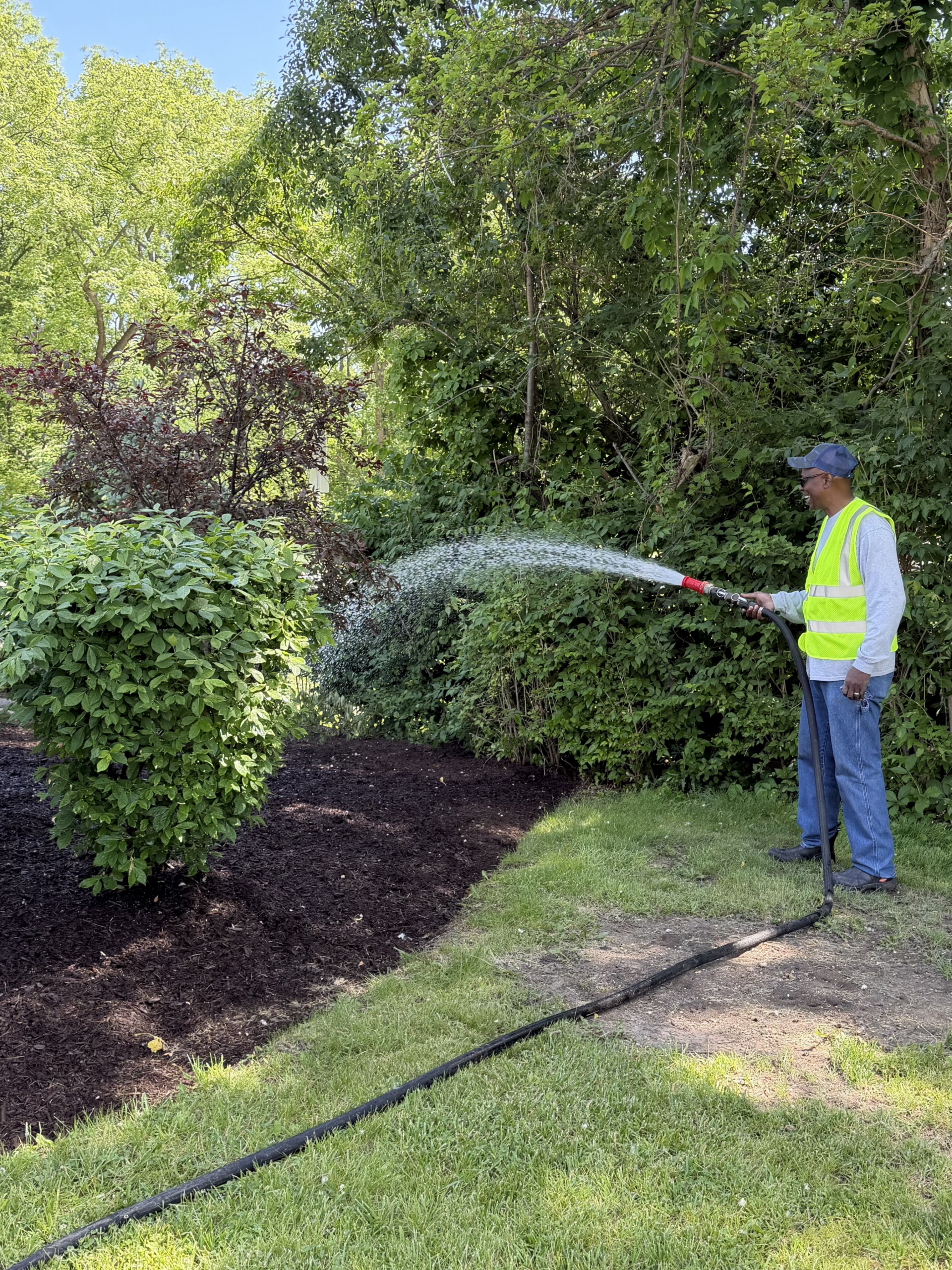 A Gasaway Maintenance Company driver watering plants with a hose.
