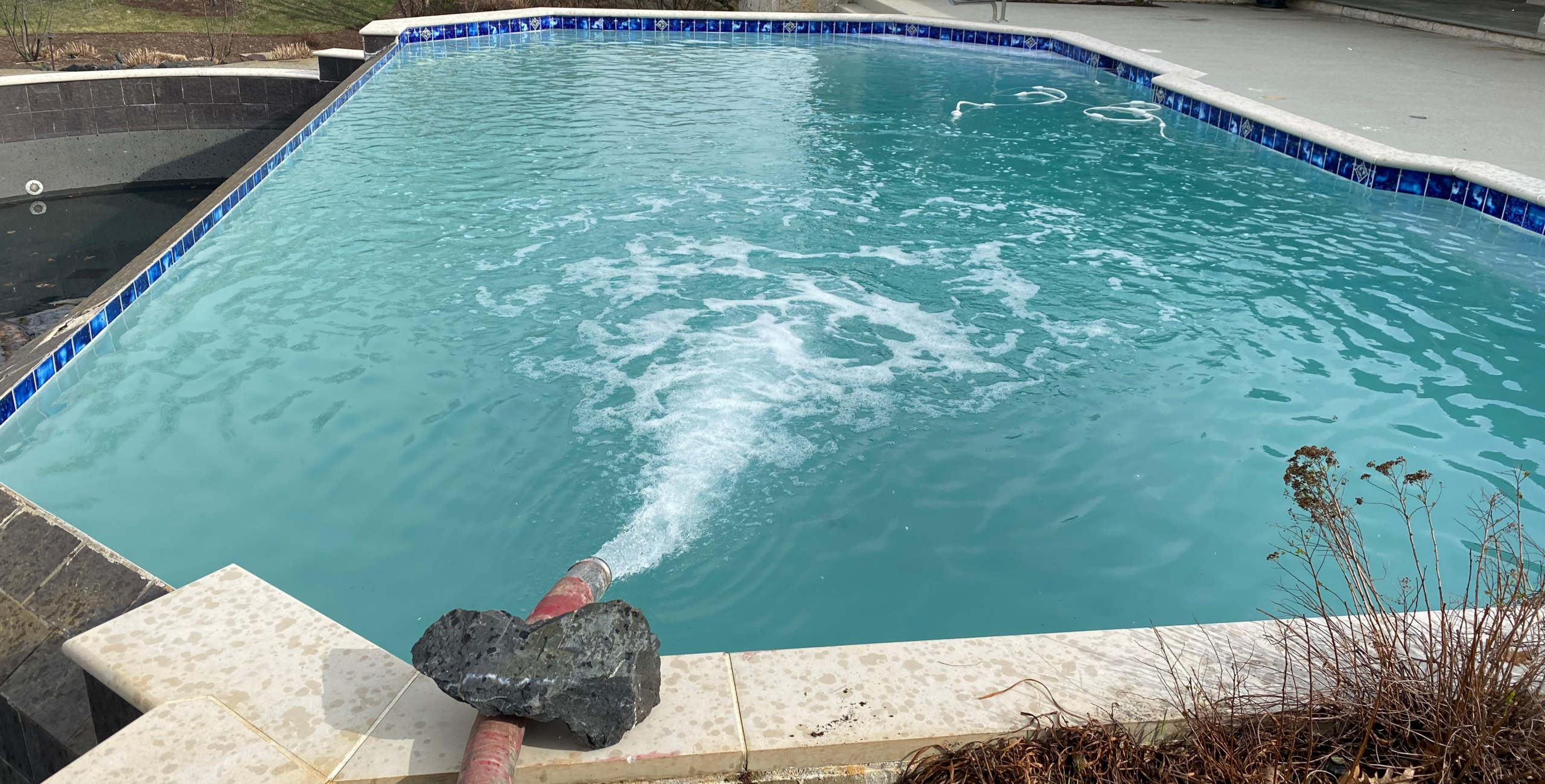 A pool in Naperville being filled by Gasaway Maintenance Company with bulk water from a powerful water hose.