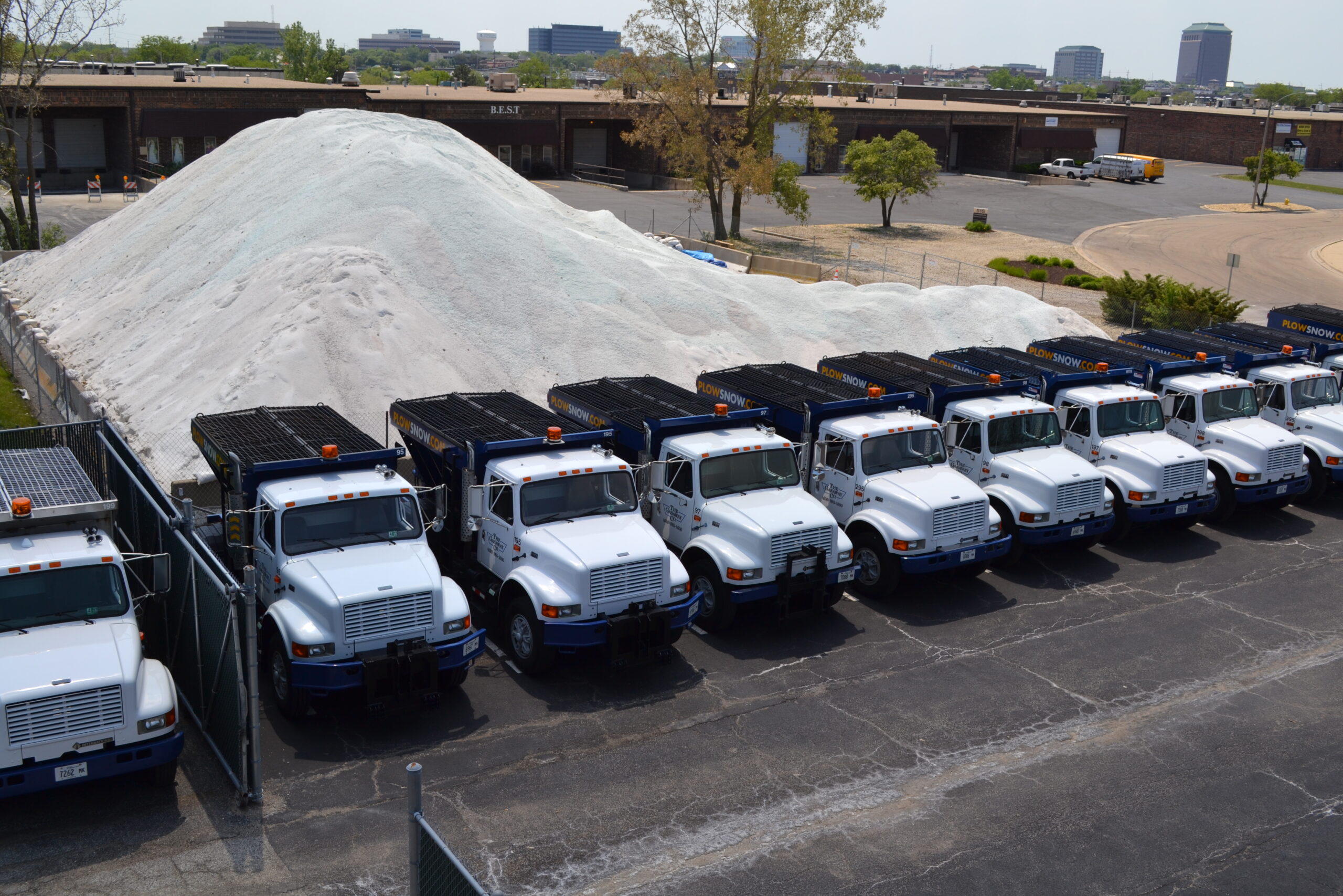 An overhead photo of 11 Gasaway Maintenance Company salt spreaders parked in front of a large pile of salt.