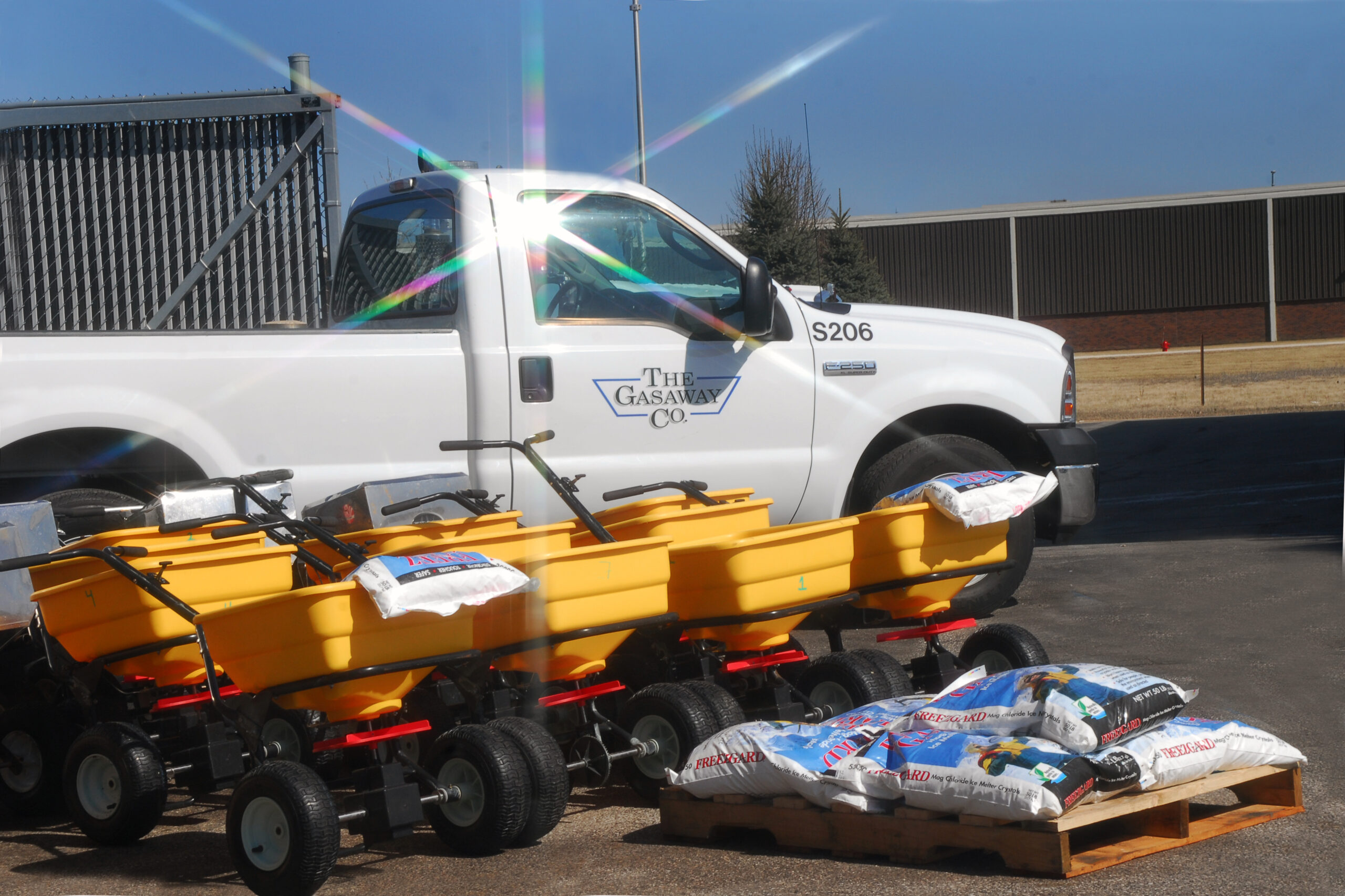 A Gasaway Maintenance Company pickup truck beaming in the sunlight, parked next to ice melt spreaders and bags of salt.